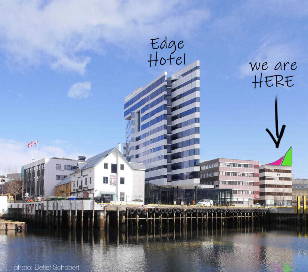View of Tromsø harbour from the water with an arrow indicating our booking point on the pier.