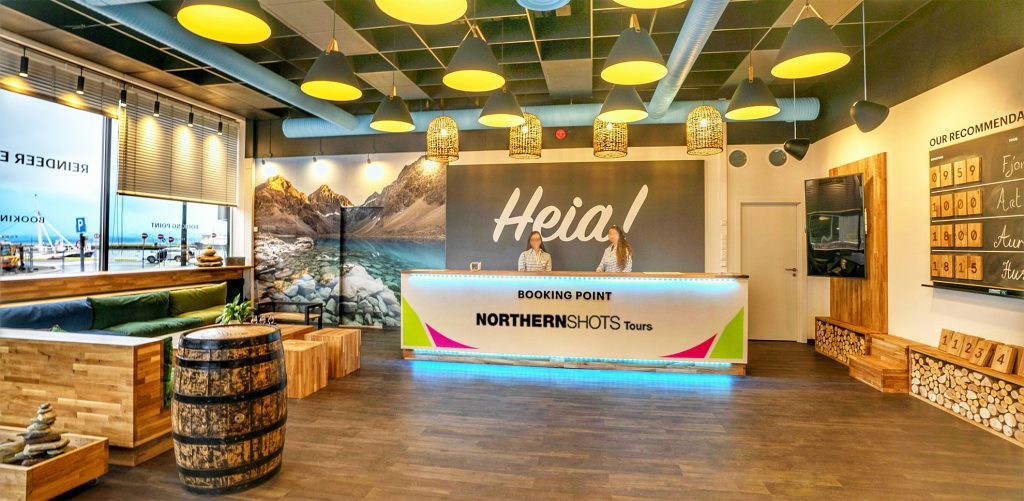 Interior of booking point with two staff members behind the counter, surrounded by a cozy lounge area.