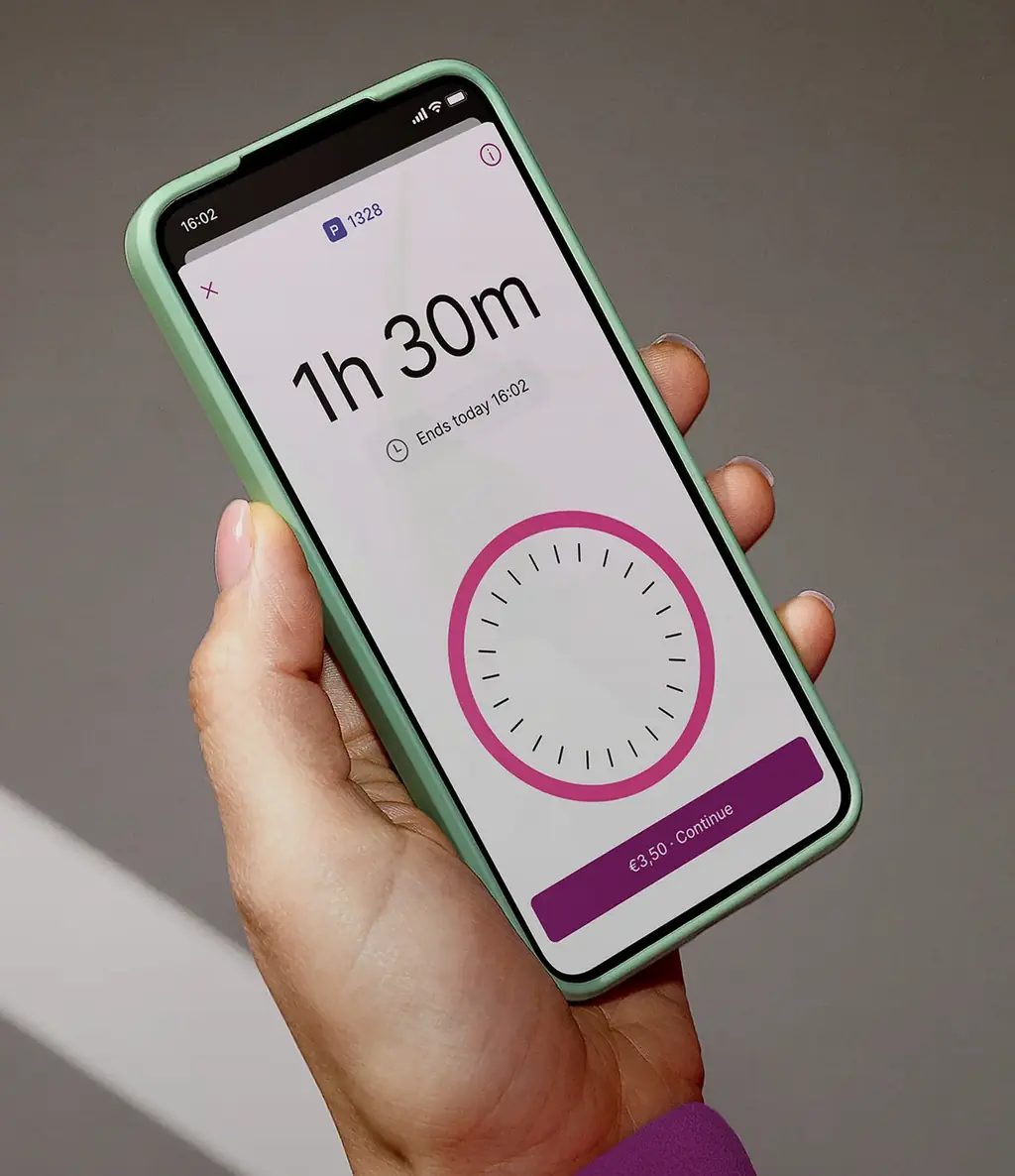 Hand holding a smartphone displaying a parking app with an active timer wheel on screen.
