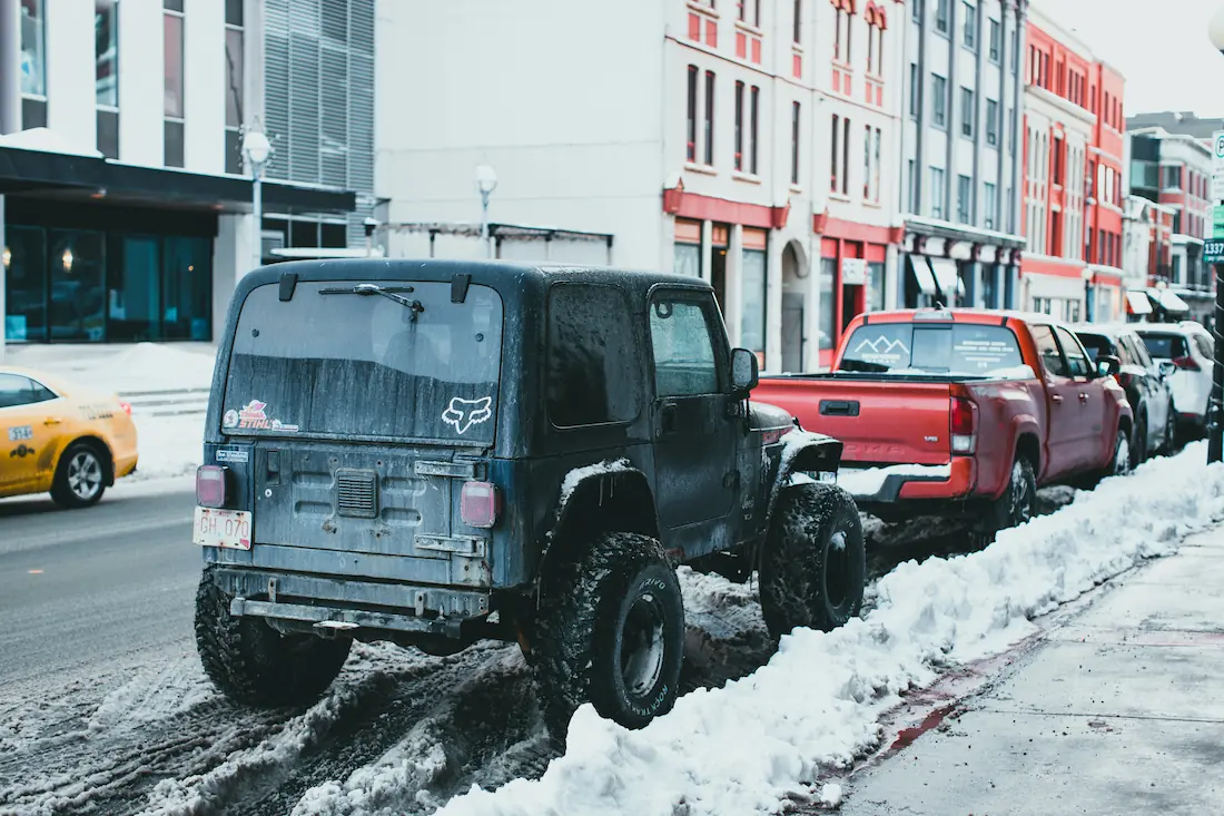 Snow-covered street in Tromsø with parked 4x4 vehicles in the urban centre.