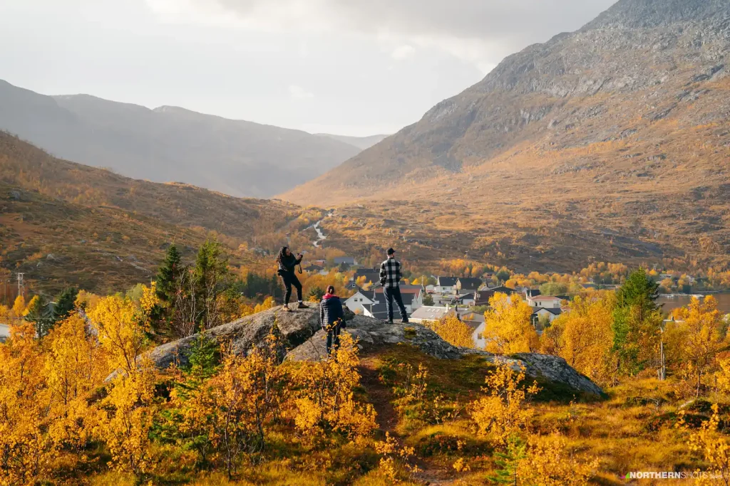 Three visitors overlooking a valley on Kvaløya, bathed in autumns colours.